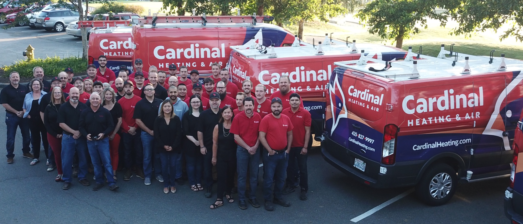 Cardinal Heating and Air employees standing behind their fleet of wrapped commercial vehicles