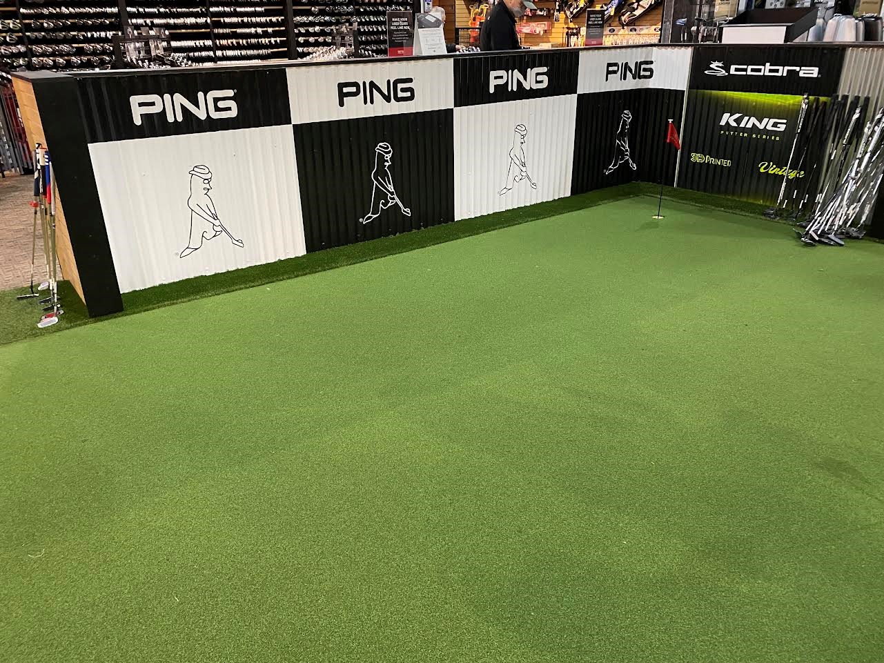 Vinyl graphic attached to corrugated metal wall surrounding putting area